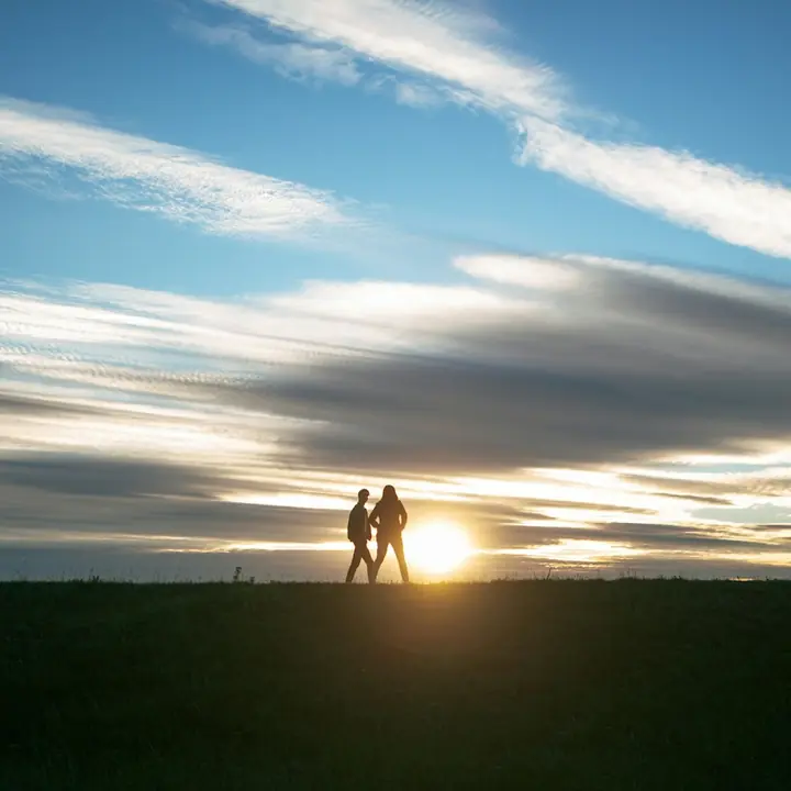 Dos siluetas en un campo frente al sol