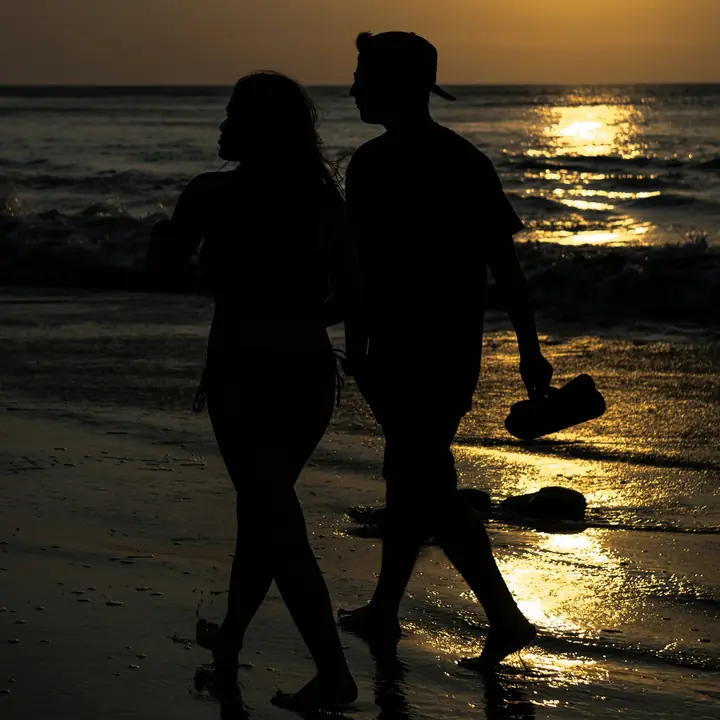 Una pareja camina por la orilla del mar al atardecer